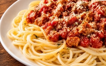 Mounds of spaghetti noodles smothered with meat sauce and mozzarella cheese.